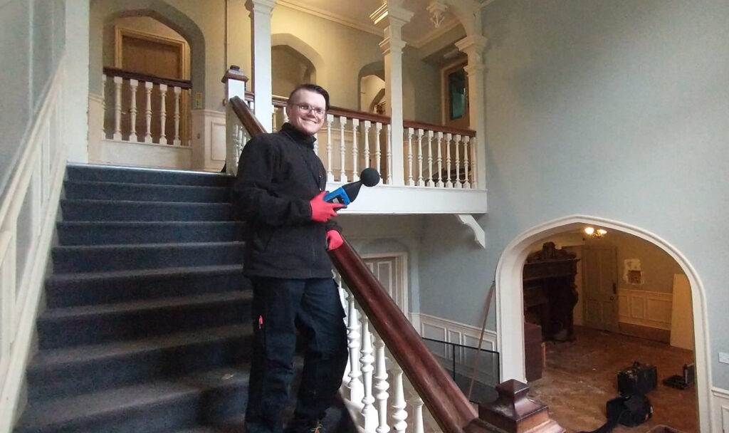 Consultant taking sound readings on a staircase.