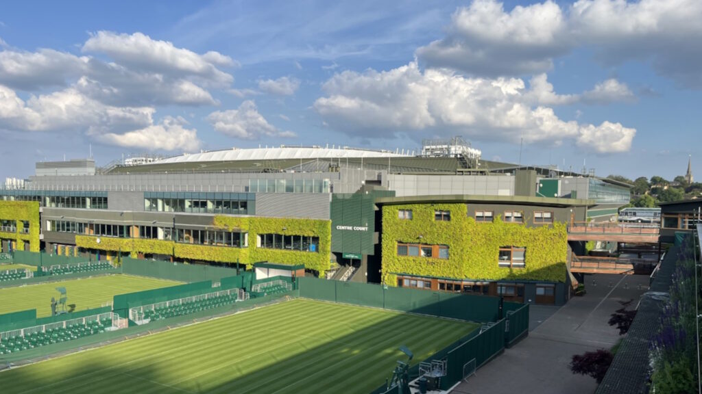 Two tennis courts with stadium in background