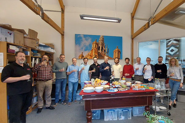 13 staff standing by a table and raising glasses